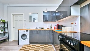 A compact kitchen with a washing machine, a stove, and a microwave. - Portrush Harbour Apt Walk to Beach (Portrush)