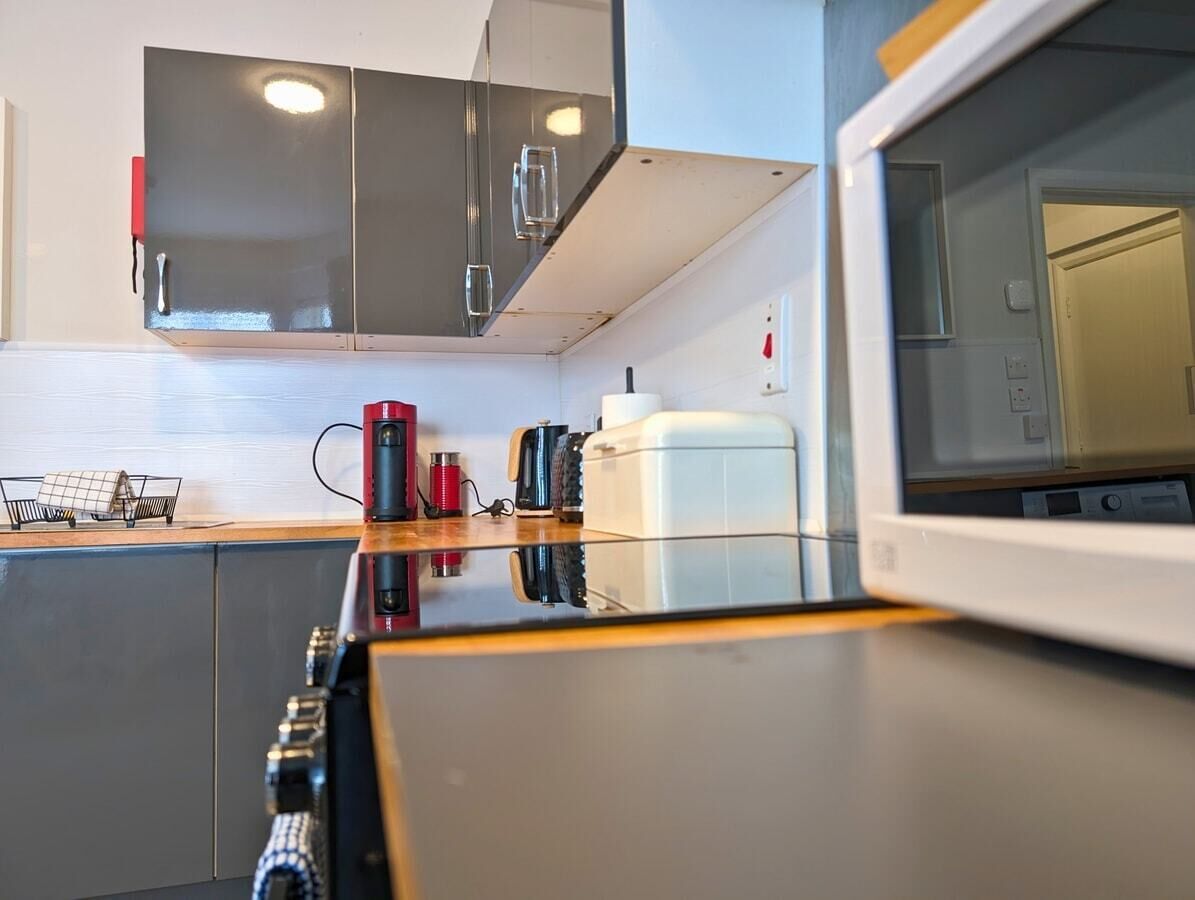 Une cuisine moderne avec des meubles gris, un four à micro-ondes et une machine à café.