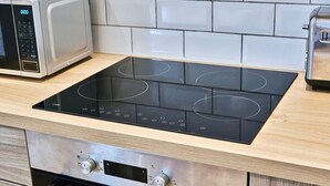 Une cuisine équipée d’une plaque de cuisson à induction noire, d’un four à micro-ondes et d’un grille-pain.