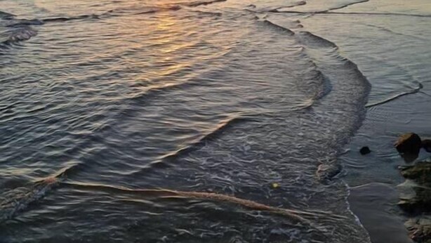 Una playa con olas y un atardecer.