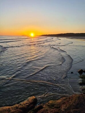Una playa con olas y un atardecer.