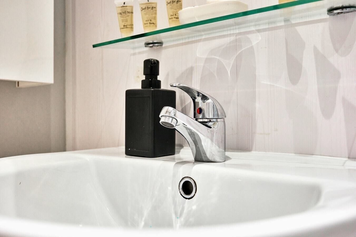A bathroom sink with a modern faucet and a black soap dispenser.