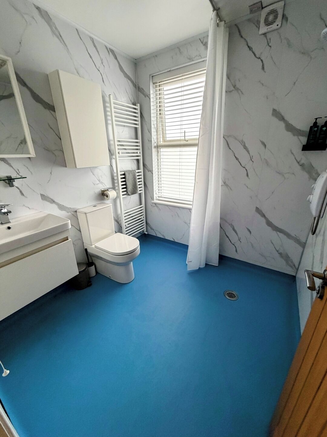 Ein Badezimmer mit Toilette, Waschbecken und einem Fenster mit Jalousien.