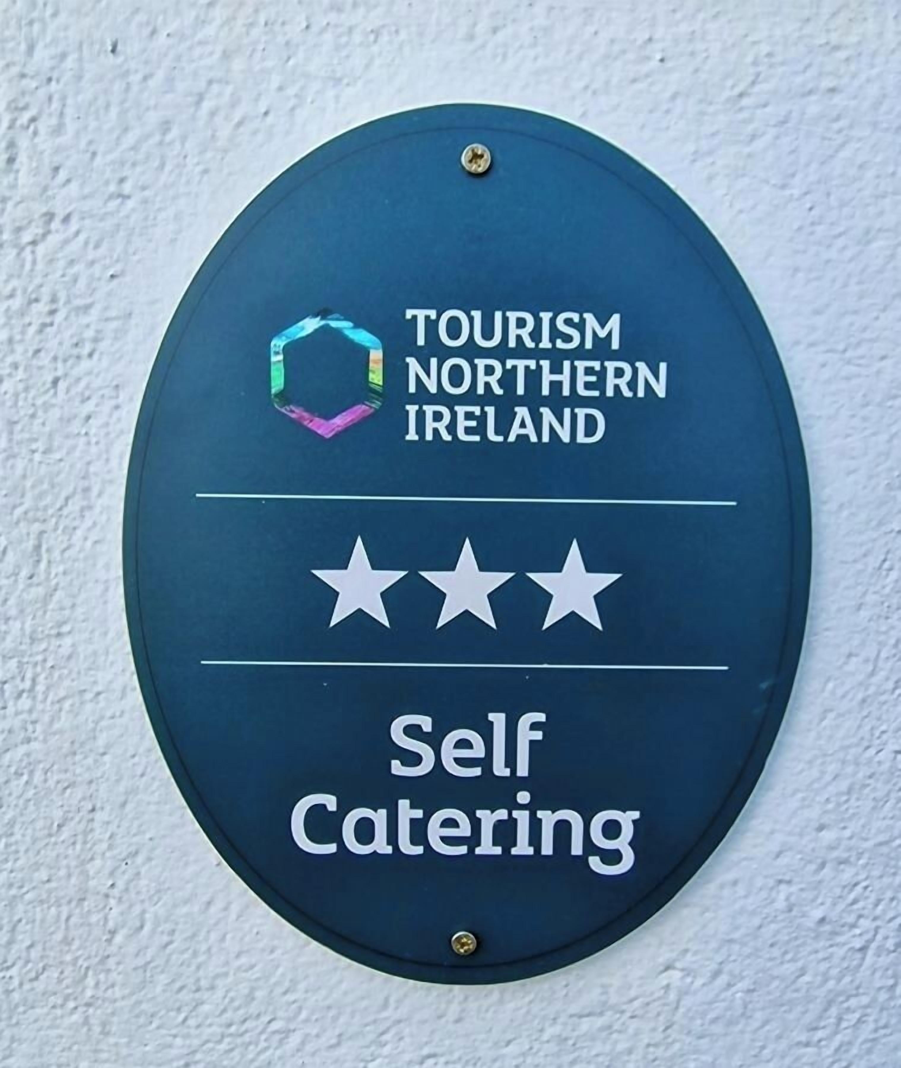 A sign for self-catering accommodation with a Tourism Northern Ireland logo and three stars.
