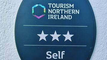 A sign for self-catering accommodation with a Tourism Northern Ireland logo and three stars.