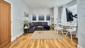 Una sala moderna con un sofá modular, una mesita redonda y un televisor sobre un mueble bajo.