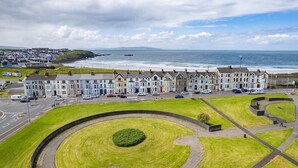 A coastal town with terraced houses, a roundabout, and a view of the sea. - Bright Apt Steps From the Beach (Portrush)
