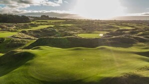A golf course with undulating terrain and a flag marking the hole.