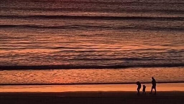 A sunset over the ocean with a beach in the foreground. - Victorian Apartment Steps to Beach (Portrush)