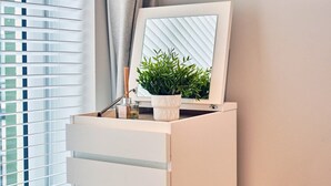 A modern room with a large window, a white cabinet, a potted plant, and a mirror. - Victorian Apartment Steps to Beach (Portrush)