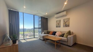 Uma sala de estar moderna com uma janela grande, um sofá, uma mesa de centro e um ar condicionado.
