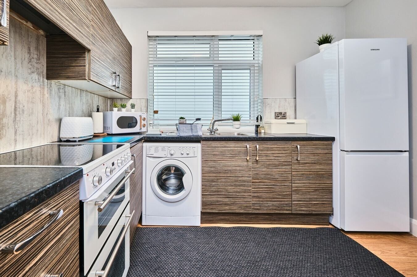 A modern kitchen with a built-in oven, microwave, and washing machine.