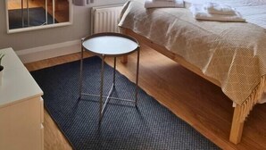 Ein Schlafzimmer mit einem Etagenbett, einem kleinen runden Tisch, einer Topfpflanze und einem Fenster mit Vorhängen.