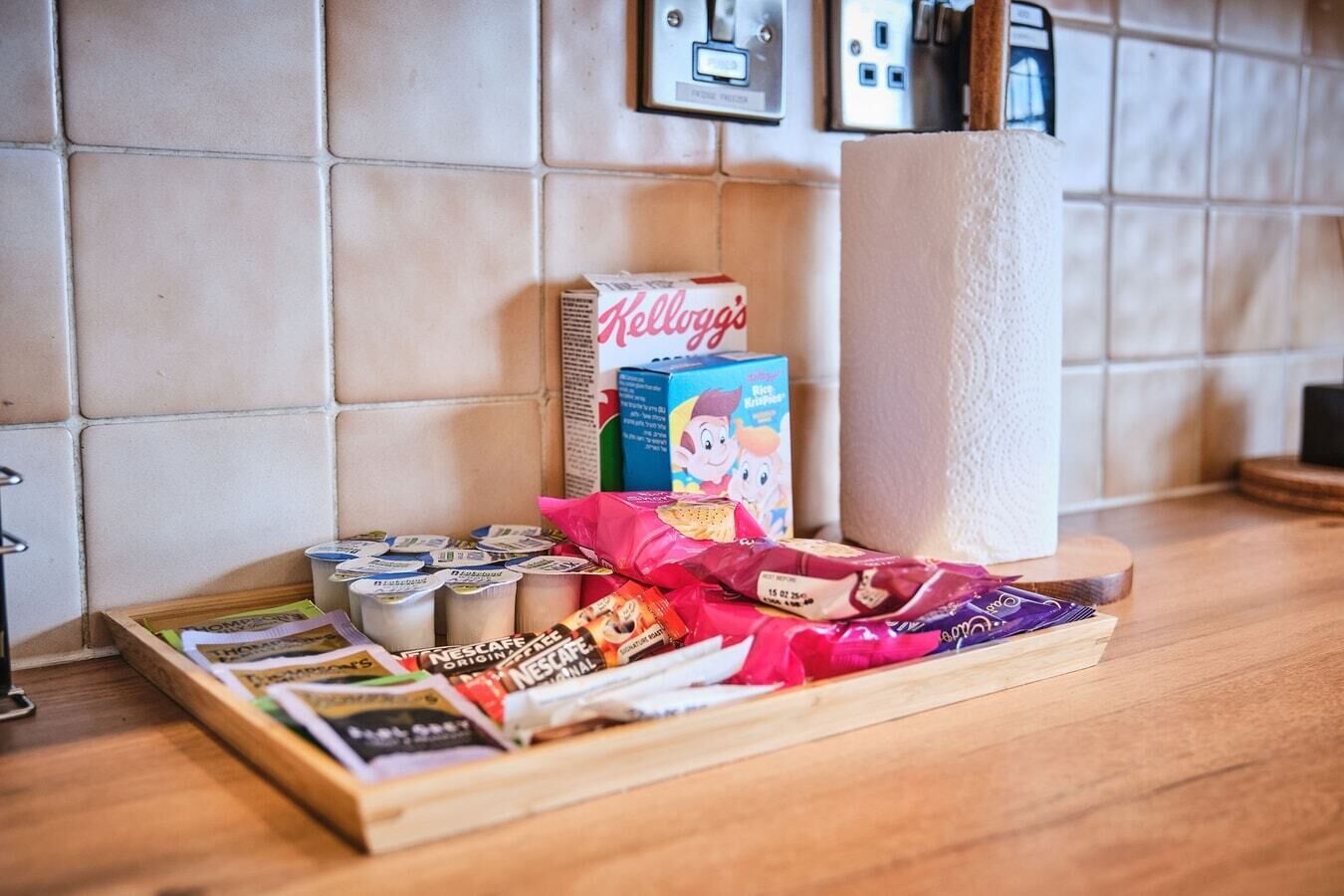 Ein Tablett mit verschiedenen Speisen und einer Schachtel Kellogg's-Cereal auf einer Holztischplatte.