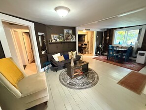 A living room with a sofa, coffee table, and a dining area with chairs and a table. - Peaceful Mountain View Retreat (Hancock)