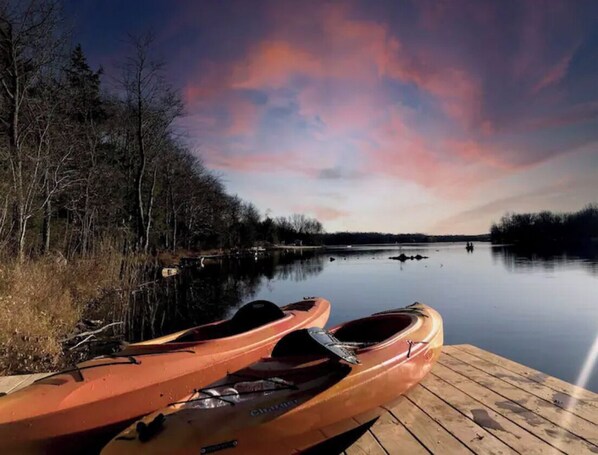 Kayaks docked on a serene lake, surrounded by dense trees.