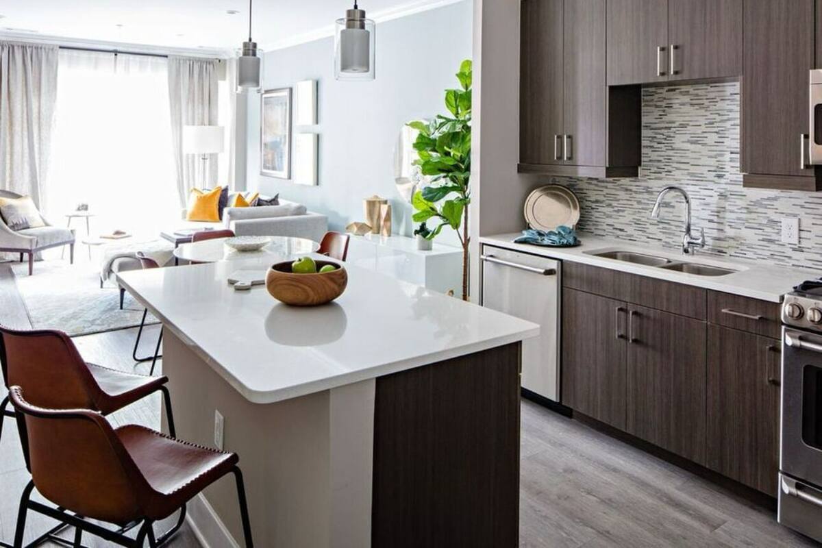A modern kitchen with dark wood cabinets, a white countertop, and a built-in stove.