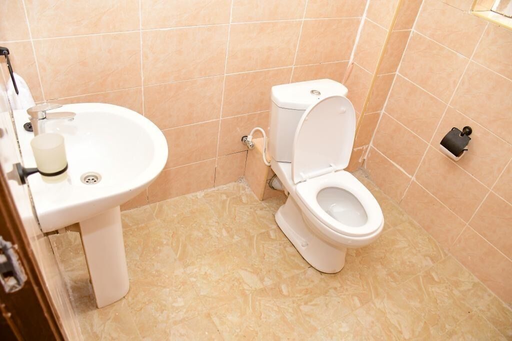 Une salle de bain avec des toilettes, un lavabo et une petite poubelle.