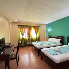 A hotel room with two beds, a desk, a television, and a window with curtains.