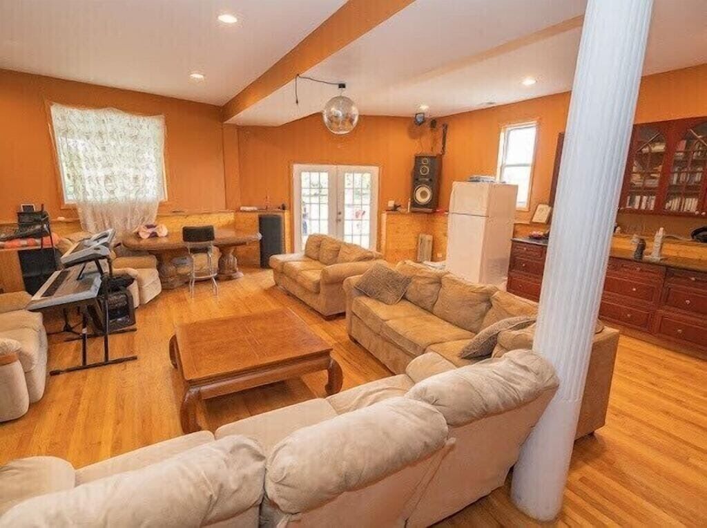 A spacious living room with a large beige sofa, a wooden coffee table, and a dining area with a small table and chairs.