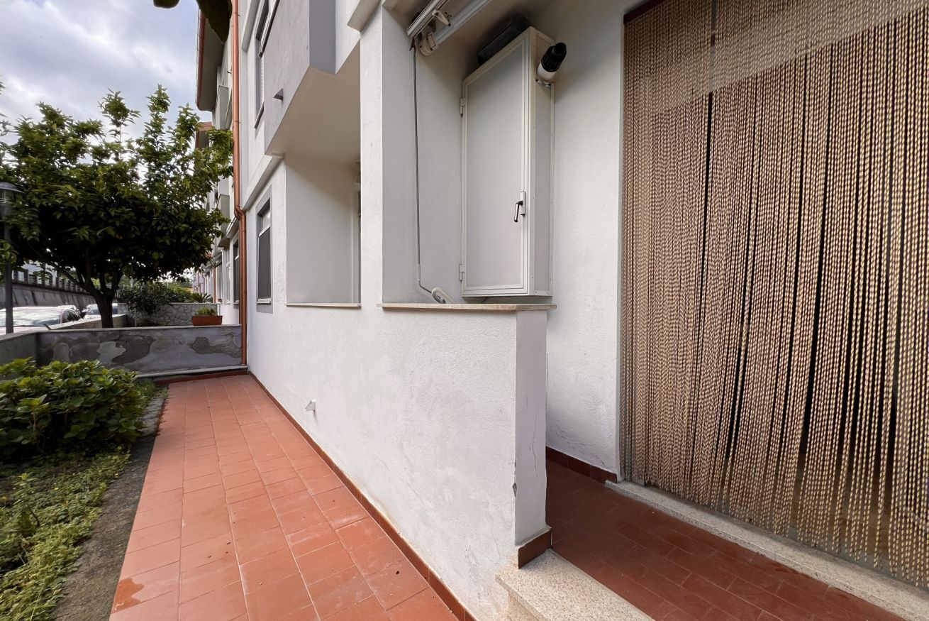 A building with a white exterior, a tiled patio, and a textured wall.