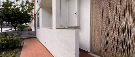 A building with a white exterior, a tiled patio, and a textured wall.