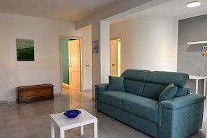 A modern living room with a teal sofa, a white coffee table, and a wooden cabinet.