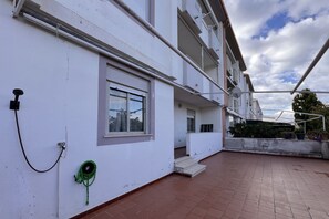 A building with a white exterior, a window, and a green hose coiled on the wall.