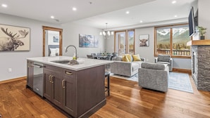 A spacious living area with a large island, a fireplace, and a view of mountains through the windows.