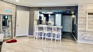 A modern kitchen with a central island, white chairs, and pendant lighting. - Modern North Scottsdale Condo – Resort Style Amenities, 1st Floor Corner Unit (Scottsdale)
