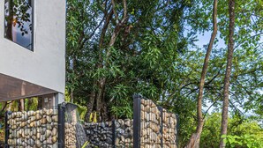 A stone-walled outdoor shower area with a wooden deck and surrounding greenery. - 3BR - Mountain View - Amazing Pool - 5 min to the Beach - Guanacaste (Puerto Carrillo)
