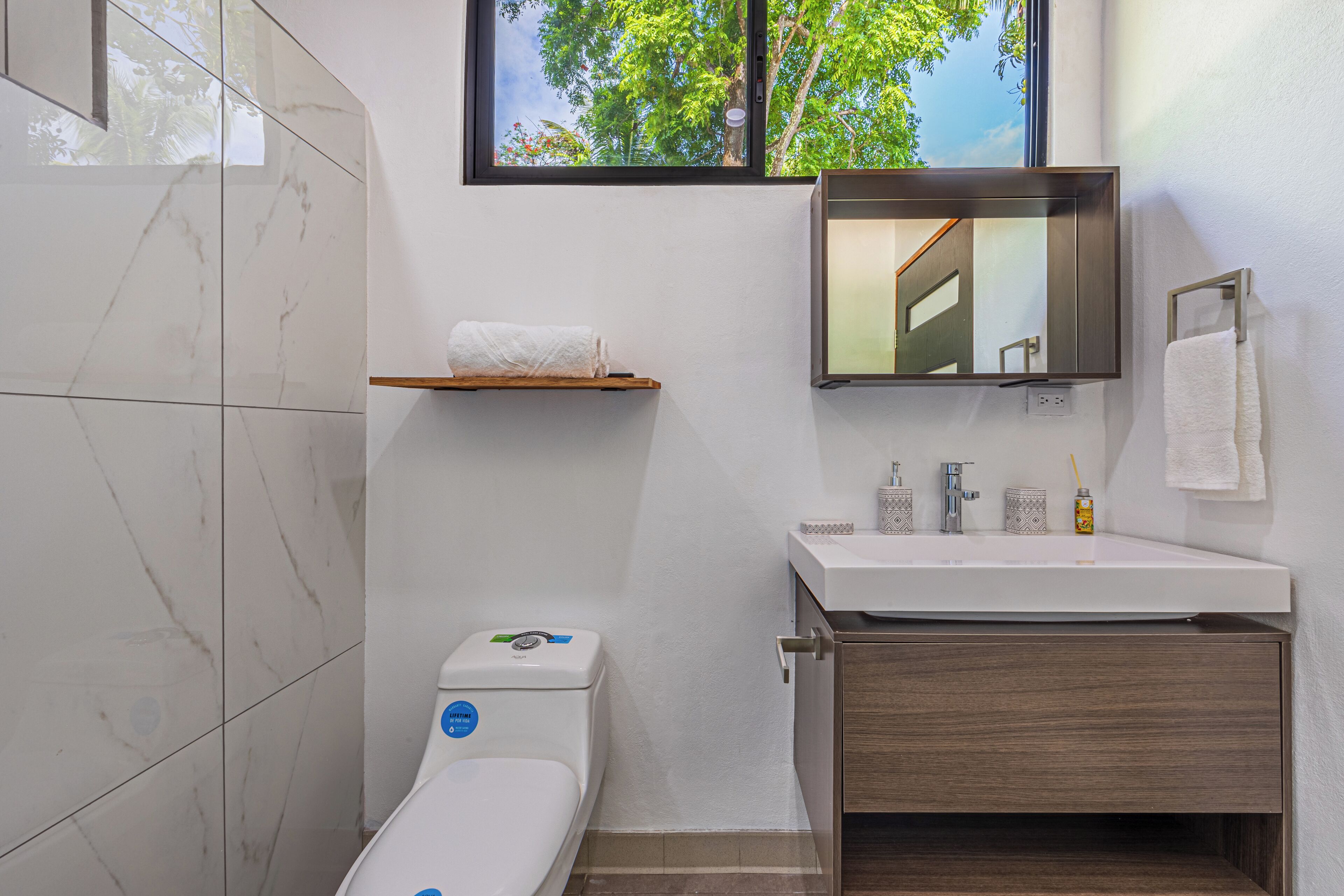 A modern bathroom with a toilet, sink, and mirror.