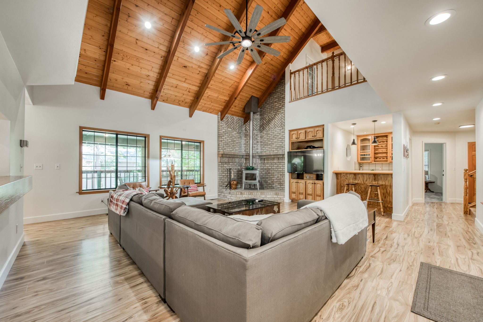 A spacious living room with a large sectional sofa, wooden ceiling beams, and a fireplace.