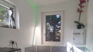 Een keuken met een ingebouwde oven, magnetron en gasfornuis. Er is een raam met uitzicht op bomen en een potplant op het aanrecht.
