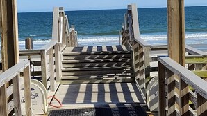 A wooden boardwalk leading to the beach with a clear view of the ocean.