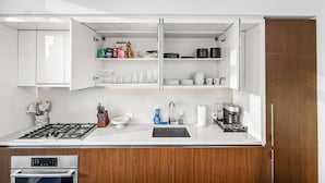 A modern kitchen with white cabinetry, a built-in stove, and a sink.
