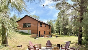 A wooden house with a deck, outdoor seating, and a hammock. - Bear Paw Lodge • Luxury Cabin • Game Room • Fire Pit (Wisconsin Dells)