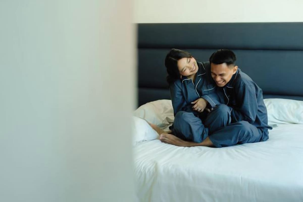 A couple sitting on a bed in a hotel room.