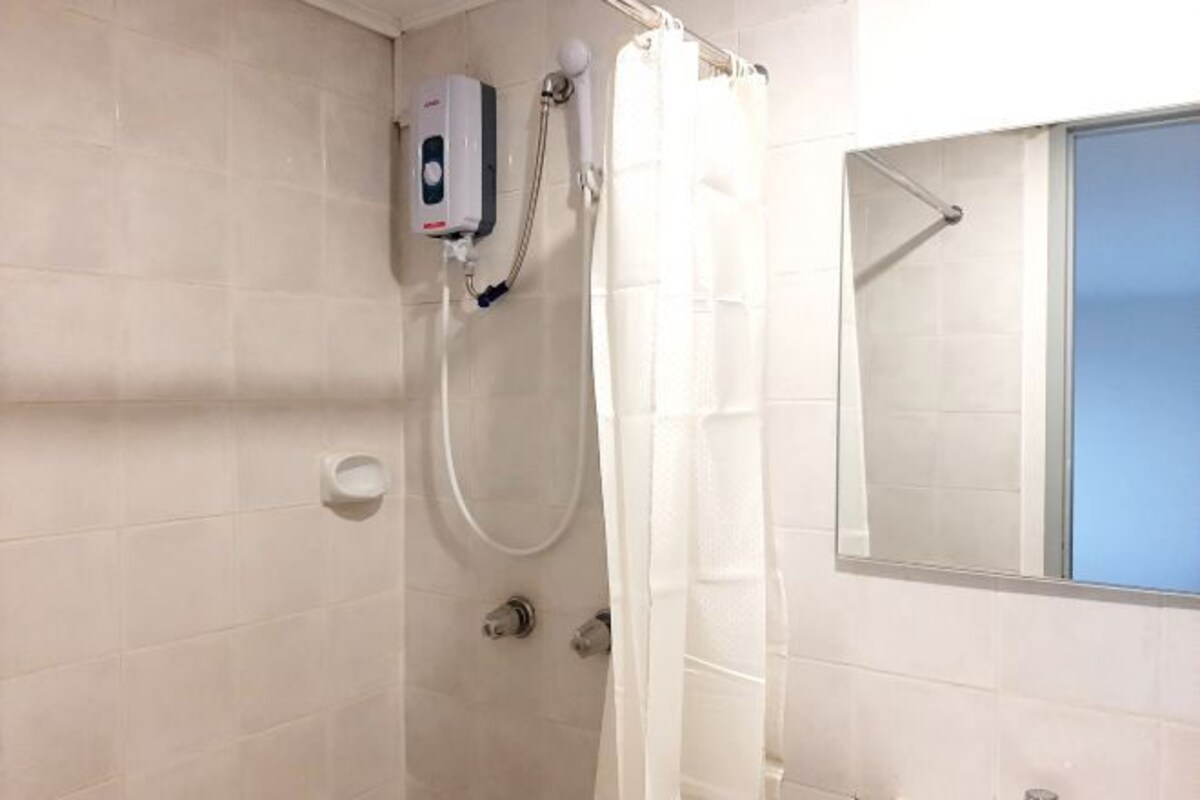 A bathroom with a shower, a hand dryer, and a mirror.