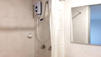A bathroom with a shower, a hand soap dispenser, and a mirror.