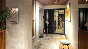 A hallway with a wooden ceiling, a reception desk, a chair, a plant, and a fire extinguisher. - Anex Hotel-Manila (Manila)