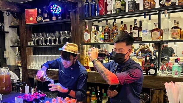 A bar area with shelves stocked with various liquor bottles and a bartender preparing drinks. - Anex Hotel-Manila (Manila)