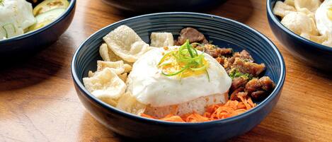 A table with four bowls containing various dishes, including rice, vegetables, and meat.