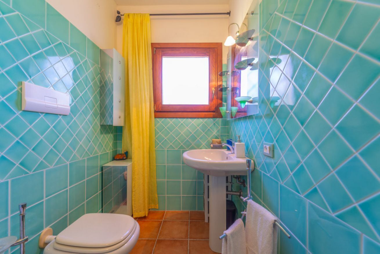 A bathroom with a toilet, sink, and window.