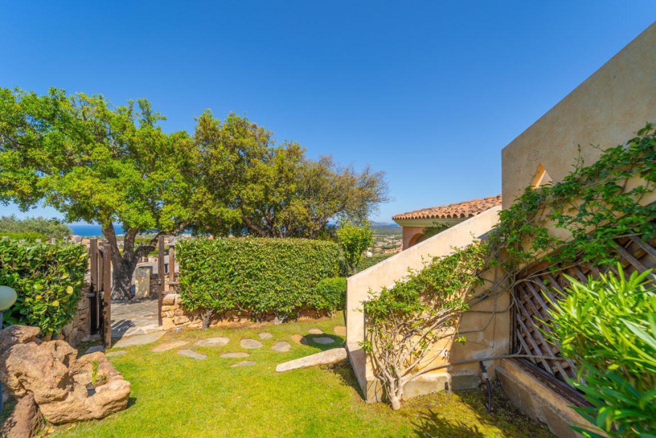 Un patio con un sendero de piedra, una puerta y vistas al mar.