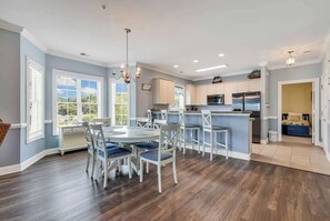 Una cocina con armarios blancos, una mesa de comedor con sillas y una isla grande.