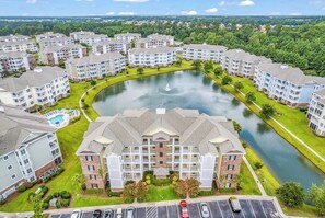 Ett bostadskomplex med en central innergård, en swimmingpool och en stor byggnad med en framträdande entré.