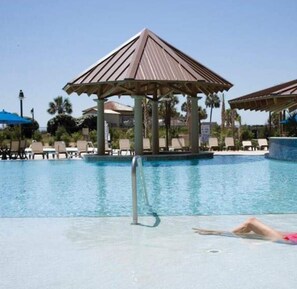 Un espace piscine agrémenté d’un belvédère, de chaises longues et surplombé d’un ciel d’un bleu limpide.
