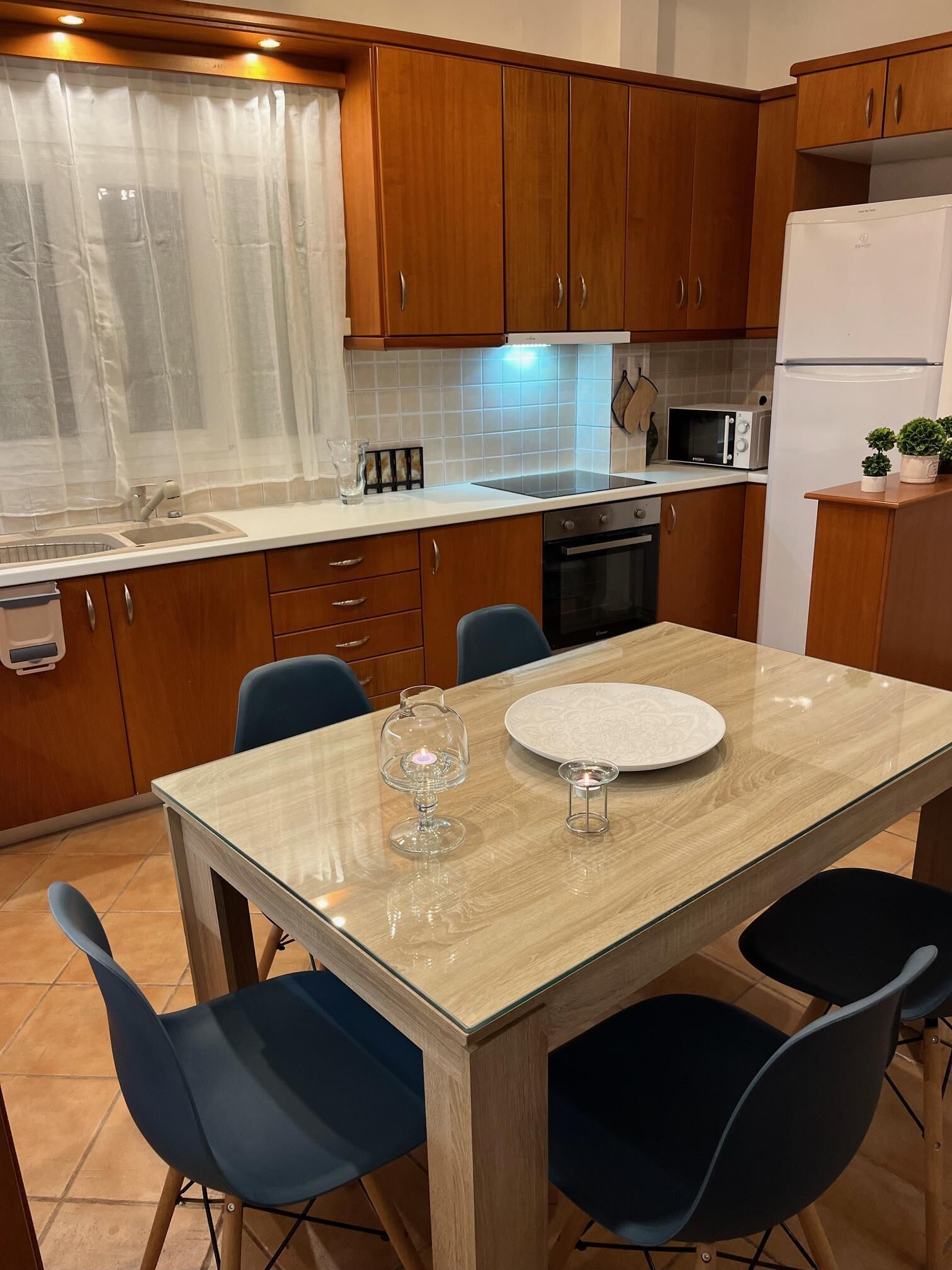 Una cocina moderna con armarios de madera, un refrigerador blanco, un microondas y una mesa de comedor con sillas.