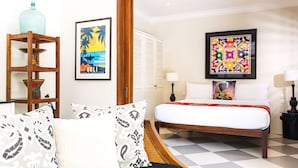 A hotel room with a bed, a wooden side table, a shelf with decorative items, and a large framed picture on the wall. - Beautiful 1 bedroom villa in perfect location (Bali)